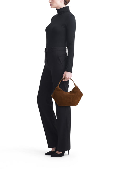 Bruine suède handtas van MANGO in een hobo-stijl, gedragen door model in zwarte kleding.