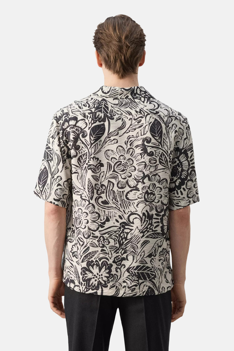 Multicolor hemd met korte mouwen van MANGO met zwart-wit bloemenpatroon, van achteren gezien met zwarte broek.