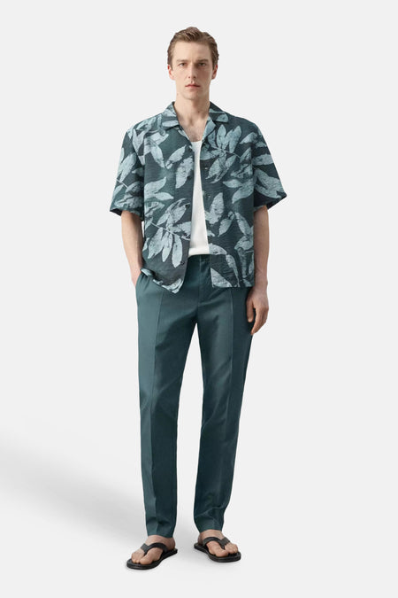 Chemise multicolore à manches courtes de MANGO, à imprimé feuilles, portée ouverte sur un t-shirt blanc.