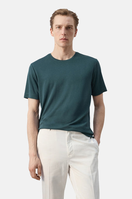T-shirt vert à manches courtes de MANGO, porté par un homme en pantalon blanc cassé, vue arrière.
