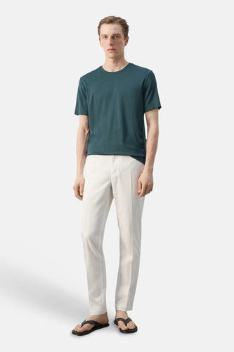 Groen T-shirt met korte mouwen van MANGO, met ronde hals, gecombineerd met een lichte broek en zwarte slippers.