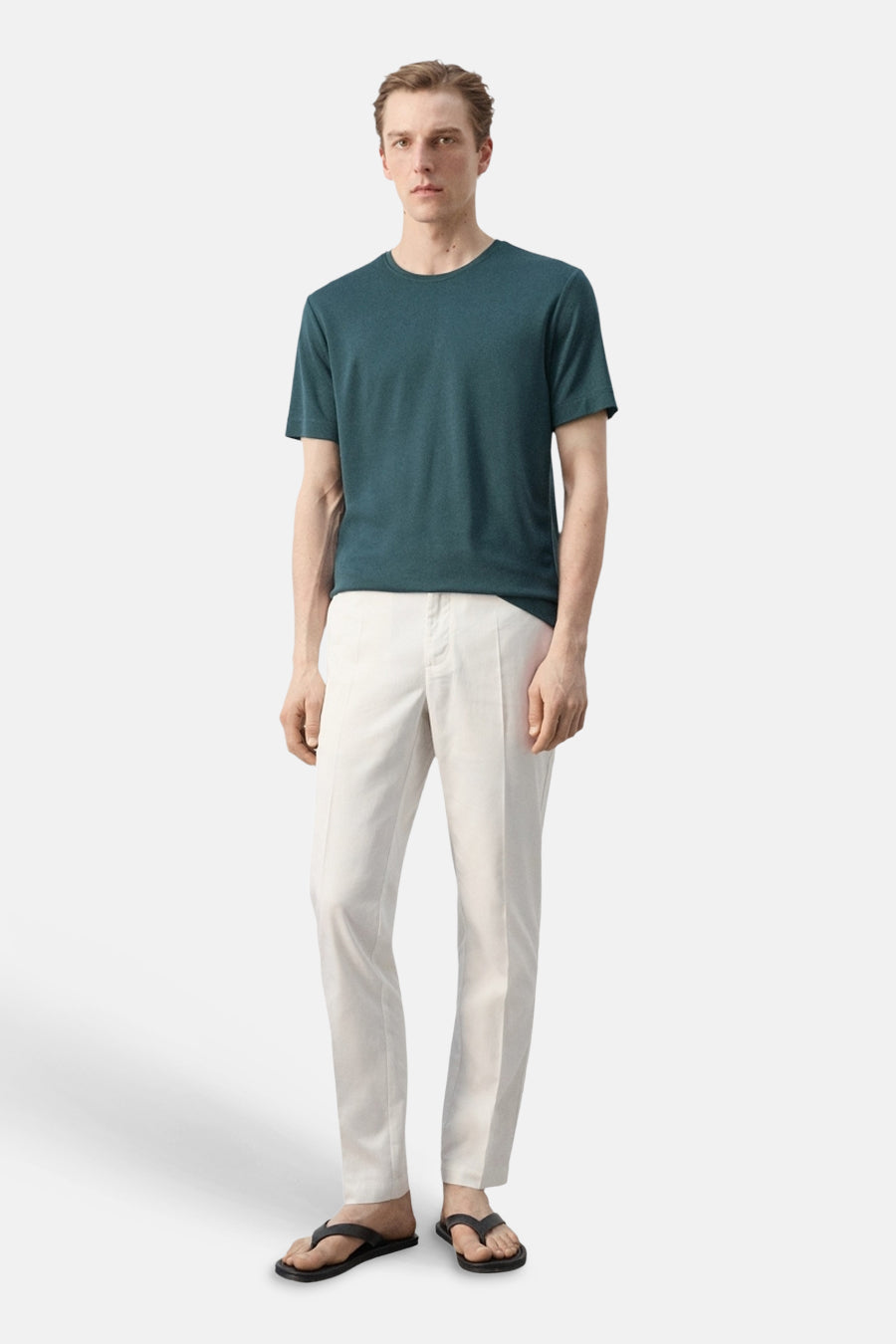 Groen T-shirt met korte mouwen van MANGO, met ronde hals, gecombineerd met een lichte broek en zwarte slippers.