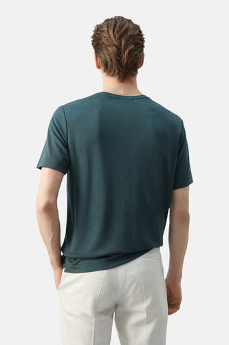Groen T-shirt met korte mouwen van MANGO, gedragen door een man in crème-witte broek, achteraanzicht.