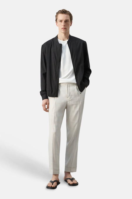 T-shirt blanc à manches courtes de MANGO, porté sous un bomber foncé avec un pantalon clair et des sandales.