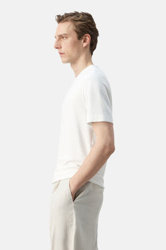 Wit T-shirt met korte mouwen van MANGO, gedragen door een man in zijprofiel met lichte broek.