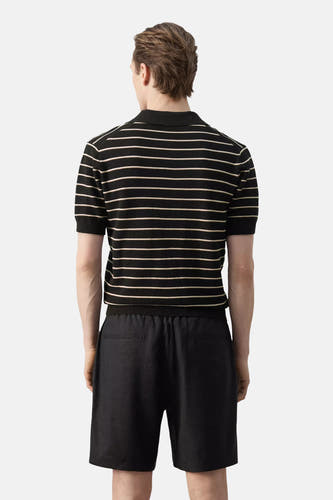 Zwarte polo van MANGO met fijne horizontale lichte strepen, korte mouwen en kraag, van achteren gezien gedragen met een zwarte korte broek.