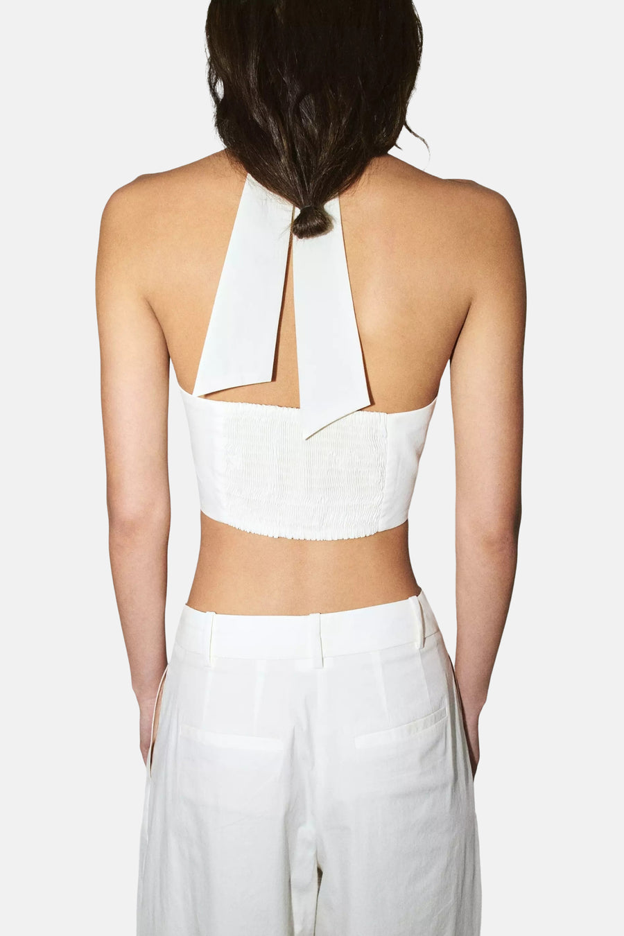 Witte mouwloze blouse met ruchedetail en V-hals van MANGO, achterkant weergegeven, model draagt witte broek