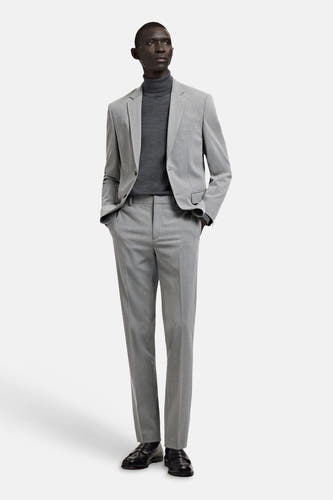 Grijze blazer van MANGO, gedragen met een grijze coltrui en een bijpassende pantalon, gecombineerd met zwarte schoenen.
