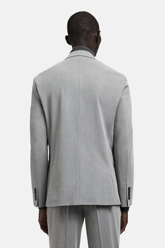 Grijze blazer van MANGO, gezien vanaf de achterkant, met donkere knopen aan de manchetten en een subtiele textuur.