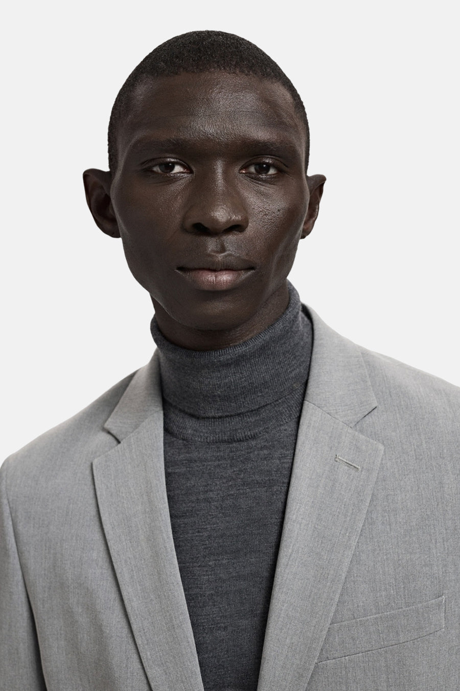 Grijze blazer van MANGO, gedragen over een grijze coltrui.
