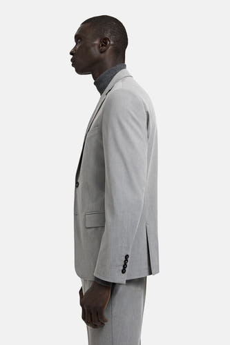 Grijze blazer van MANGO, gezien vanaf de zijkant, met lange mouwen en een grijze coltrui eronder.
