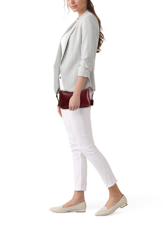 Bordeaux schoudertas van Mango, met zilverkleurige details, gedragen met een grijze blazer en witte broek.
