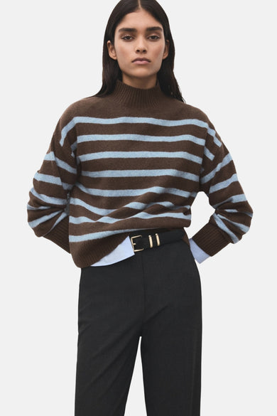Multikleurige trui met ronde hals van MANGO, met horizontale strepen in bruin en lichtblauw, gecombineerd met een zwarte pantalon en riem.
