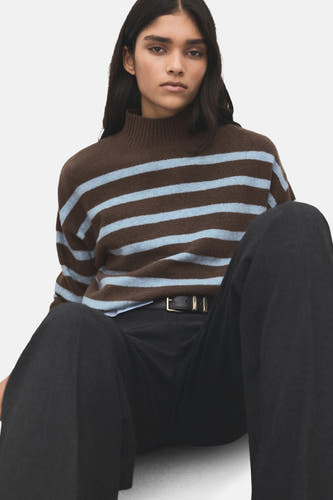 Multikleurige trui met ronde hals van MANGO, met horizontale blauwe strepen, gedragen met een zwarte pantalon en riem.
