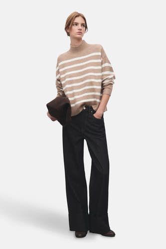Beige trui met ronde hals van MANGO, gestreept, gecombineerd met donkere jeans met wijde pijpen en bruine schoenen.