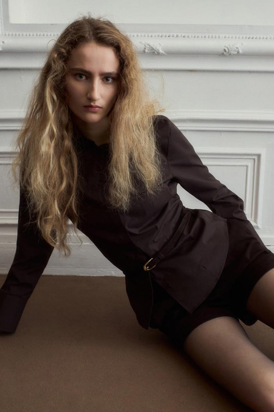 Chemise marron à manches longues de MANGO, vue de dos avec ceinture à la taille et cheveux blonds bouclés.