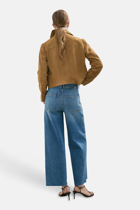 Blauw denim jeans wide van MANGO, met wijde pijpen en achterzakken, gecombineerd met een bruin jasje en hakken.
