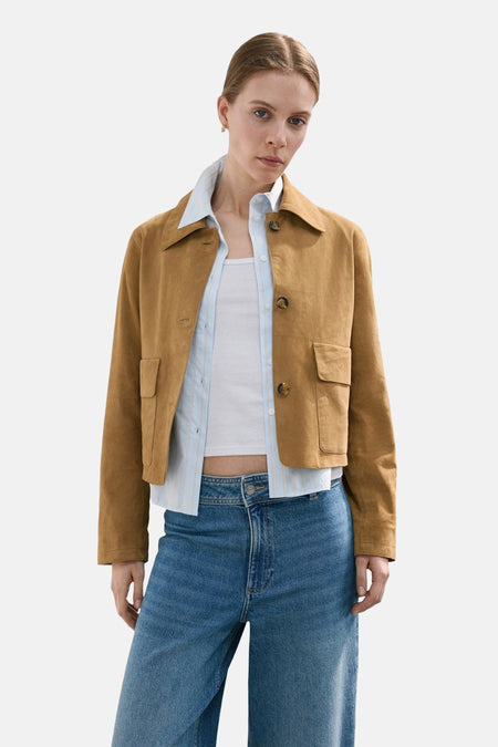 Wijde jeans van midblauw denim van MANGO, gecombineerd met een bruin jasje en een gestreept overhemd.