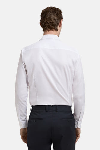 Wit overhemd met lange mouwen van MANGO, gezien van achteren, gecombineerd met donkere pantalon.
