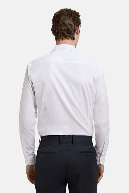 Chemise blanche à manches longues de MANGO, vue de dos, associée à un pantalon foncé.
