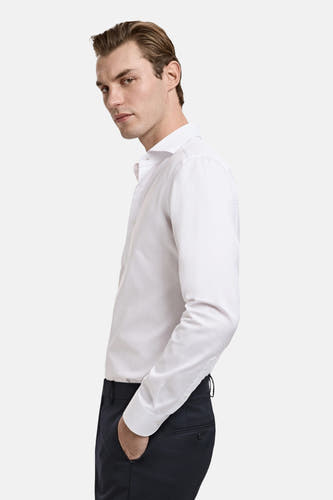 Wit overhemd met lange mouwen van MANGO, met een klassieke kraag en gedragen met donkere pantalon.
