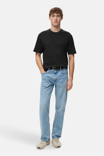 T-shirt noir à manches courtes de MANGO, porté avec des jeans bleus et des chaussures en cuir suédé, style décontracté.