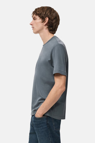 Blauw T-shirt met korte mouwen van MANGO, in profiel gezien met model in blauwe jeans.
