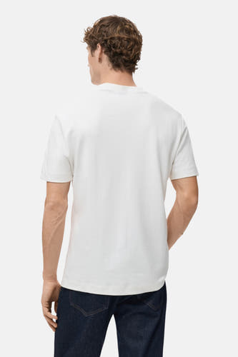 Wit T-shirt met korte mouwen van MANGO, gezien van achteren, gedragen met donkerblauwe jeans.
