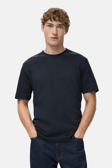Blauw T-shirt met korte mouwen van MANGO, gedragen met donkere jeans en handen in de zakken.