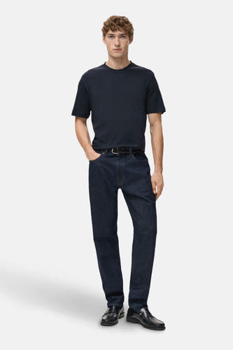 T-shirt bleu à manches courtes de MANGO, porté avec des jeans foncés et des loafers en cuir noirs.