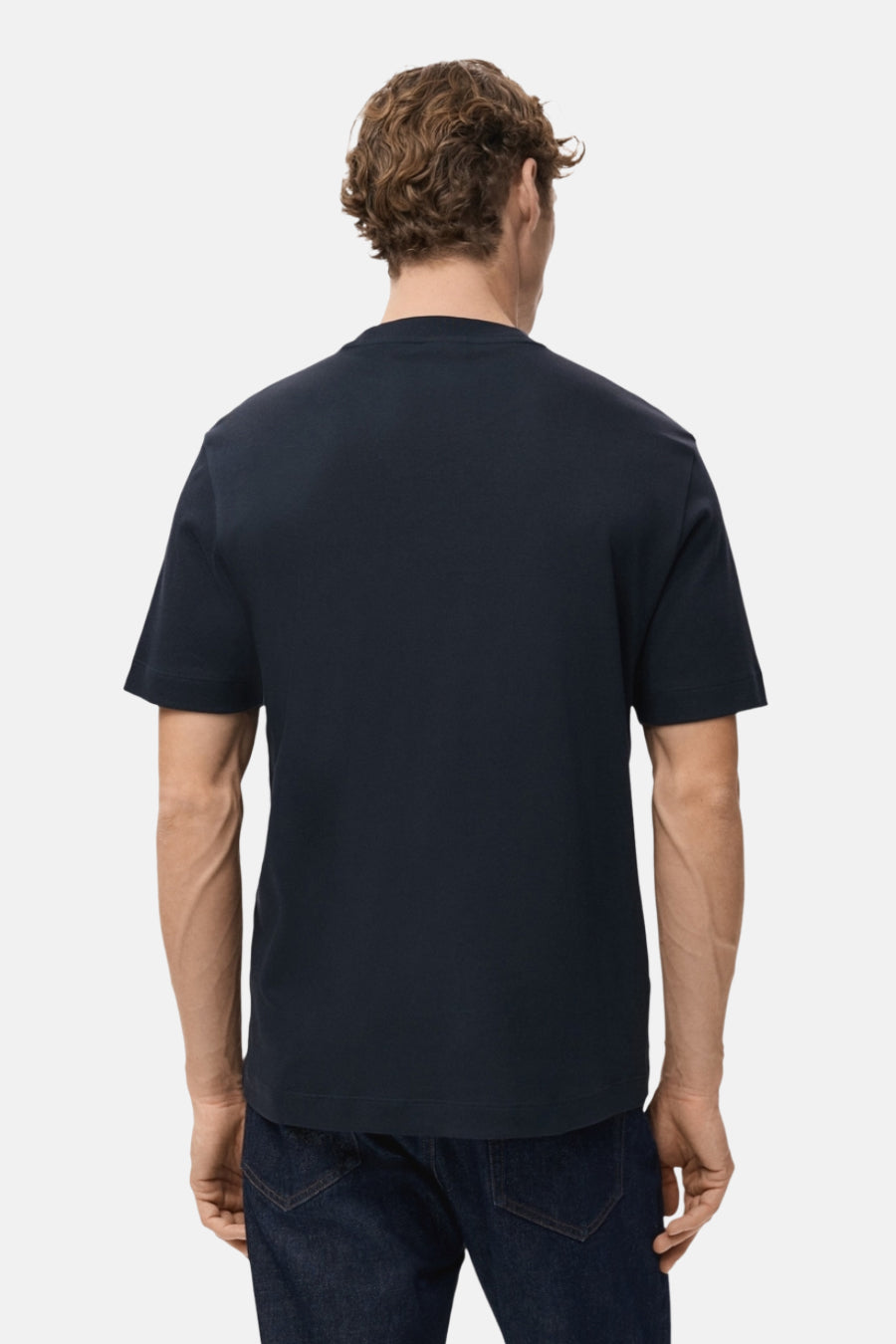 Blauw T-shirt met korte mouwen van MANGO, gezien van achteren, gecombineerd met een donkere jeans.
