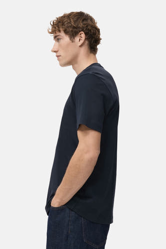 T-shirt bleu à manches courtes de MANGO, sur un modèle en vue latérale, avec des jeans foncés.