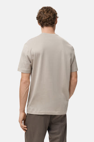 Beige T-shirt met korte mouwen van MANGO, gezien van achteren, gecombineerd met een bruine pantalon.