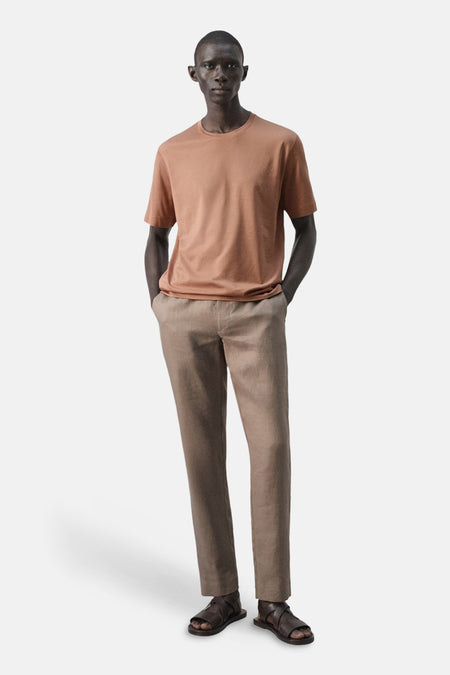 T-shirt marron à manches courtes de MANGO, porté avec un pantalon ample et des sandales.