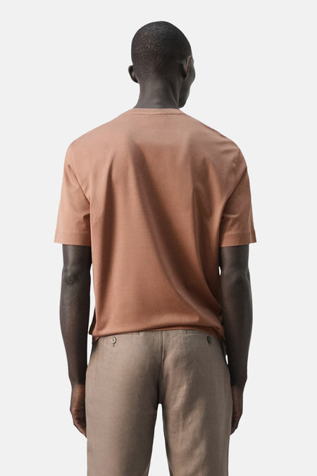 Bruin T-shirt met korte mouwen van MANGO, achterkant zichtbaar, gecombineerd met een beige broek.
