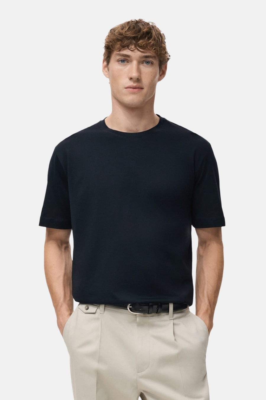 Blauw T-shirt met korte mouwen van MANGO, gedragen met een beige pantalon en een zwarte riem.
