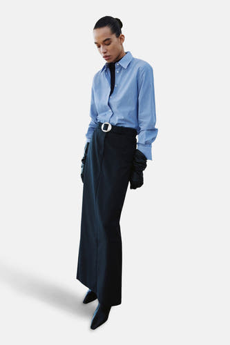 Blauw gestreept overhemd met lange mouwen van MANGO, gedragen met een zwarte coltrui, lange rok, riem en handschoenen.
