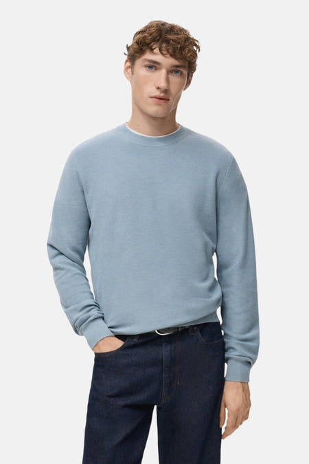 Blauwe trui met ronde hals van MANGO, gedragen met donkere jeans en een zwarte riem.
