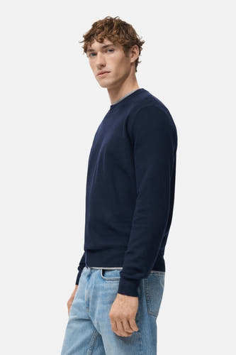 T-shirt bleu avec col rond de MANGO, porté avec un jean bleu clair en vue latérale.