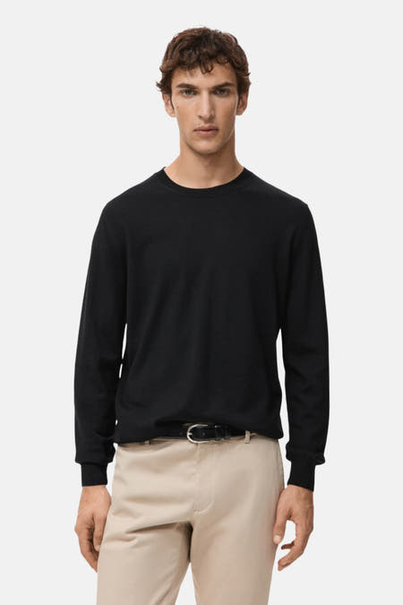 Zwarte trui met ronde hals van MANGO, gedragen met beige broek en zwarte riem.
