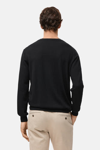 Zwarte trui met ronde hals van MANGO, gezien van achteren, gecombineerd met een beige pantalon.
