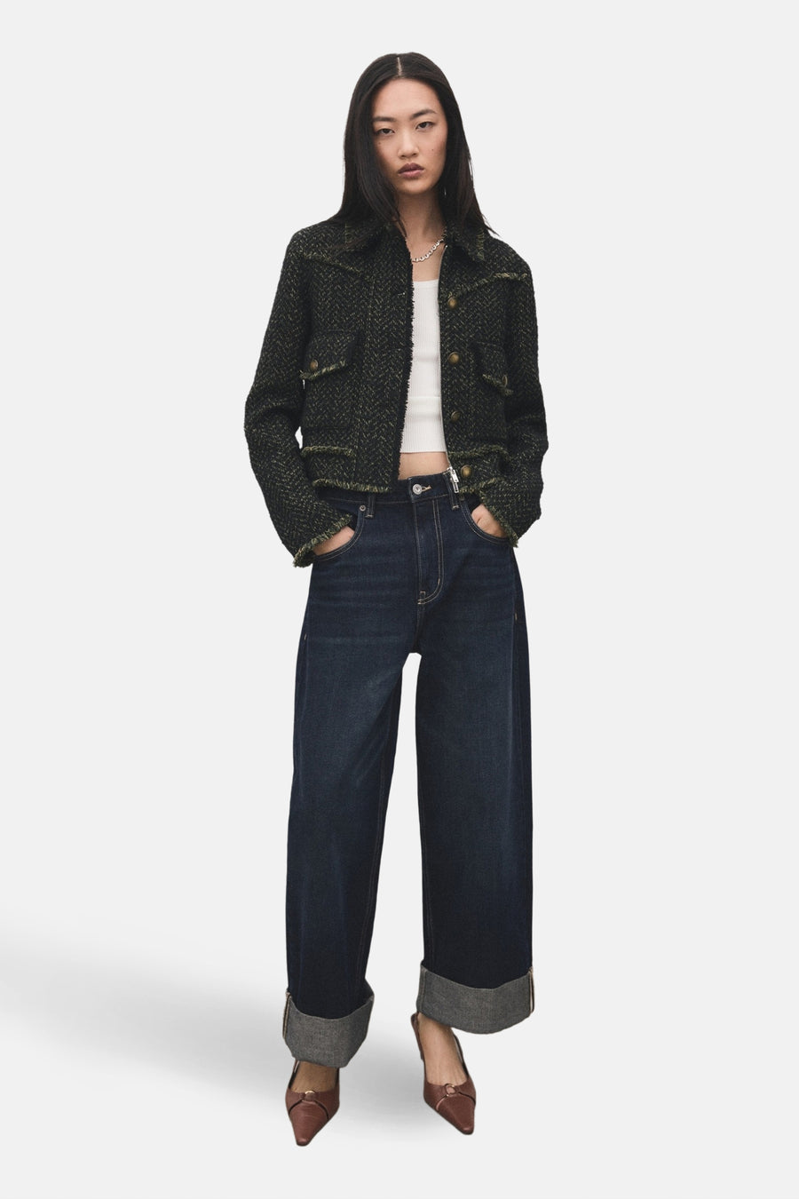 Blazer vert de MANGO, avec un motif tweed texturé et des boutons dorés, associé à une chemise blanche et des jeans larges.
