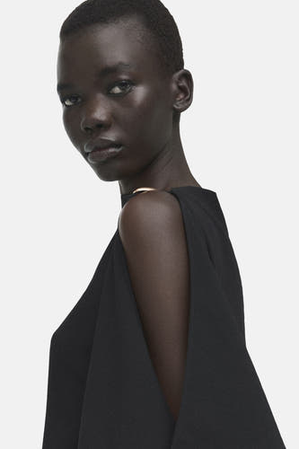 Zwarte mouwloze blouse van MANGO, met een open schouder en een goudkleurige halslijn.