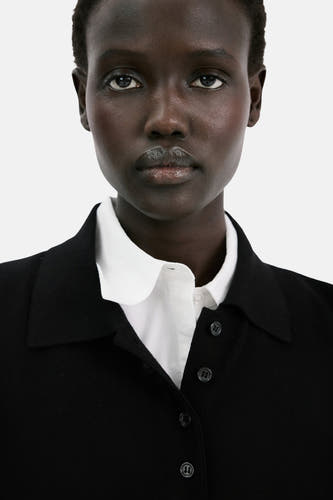Polo noire à manches courtes de MANGO, portée sur un t-shirt blanc à col rond.