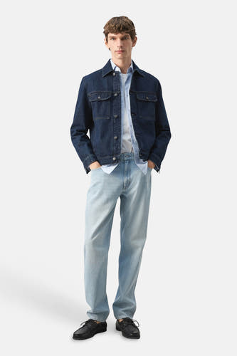 Veste en jean bleu marine de MANGO, avec poches plaquées et coupe décontractée, portée sur une chemise rayée.