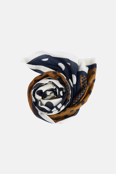 Multikleurige zomersjaal van MANGO, met een stippenpatroon in wit, donkerblauw en bruin, opgerold.
