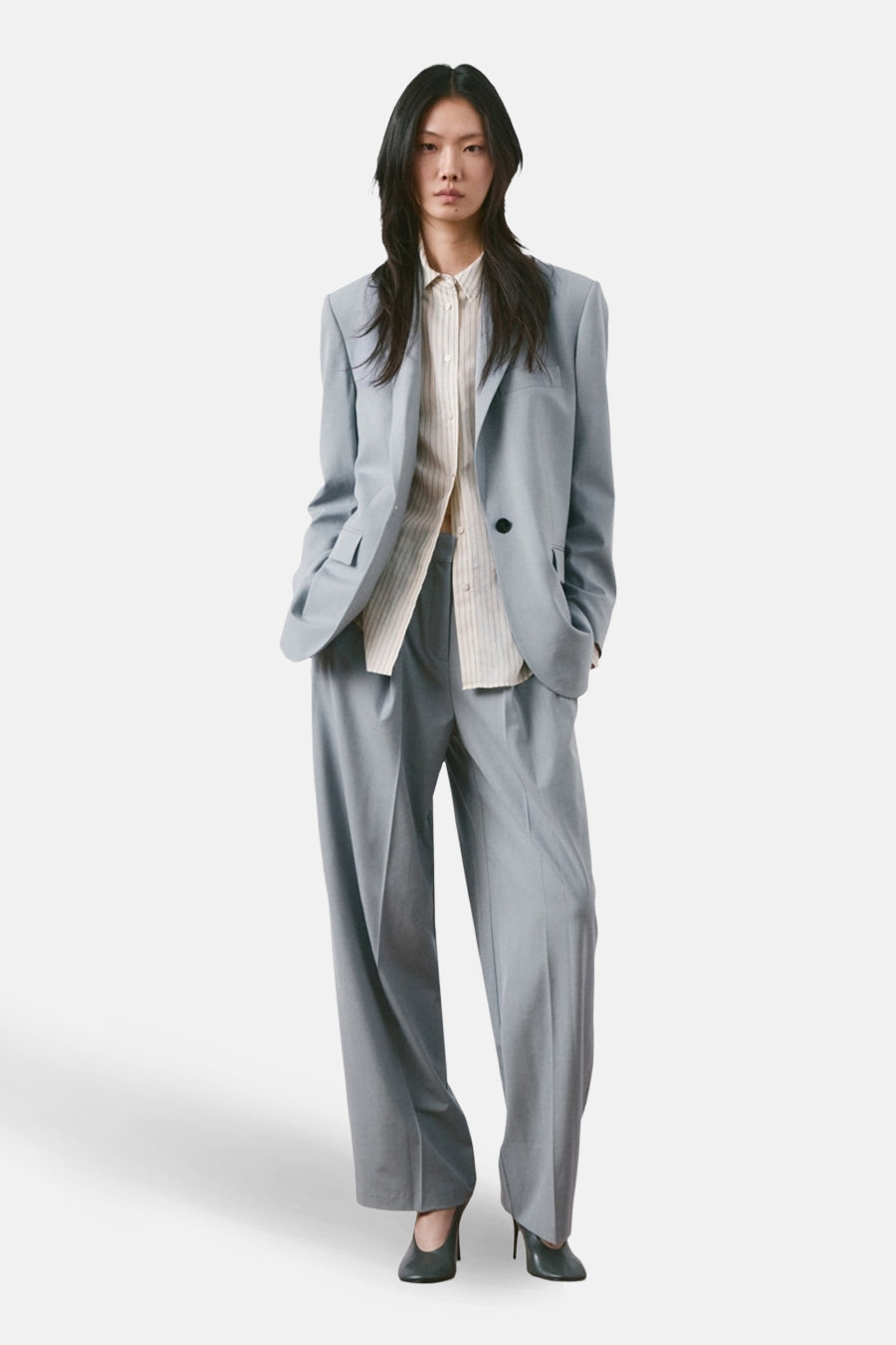 Blazer bleu de MANGO, porté sur une chemise rayée et assorti à un pantalon assorti.