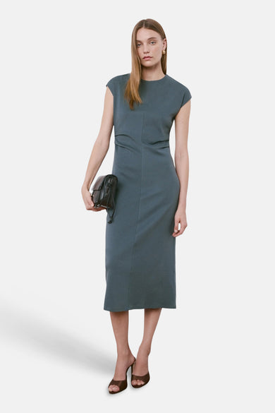Robe bleue sans manches de MANGO, avec une longueur au-dessus du genou et des mules marron.