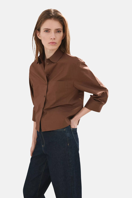Chemise marron de MANGO avec manches longues retroussées, vue de dos sur mannequin avec jean foncé et tongs.