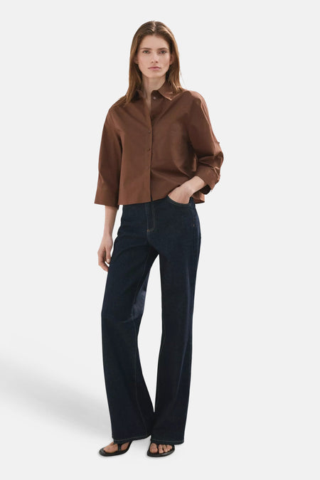 Chemise marron de MANGO avec manches 3/4 et col, stylisée avec un jean foncé et des tongs.